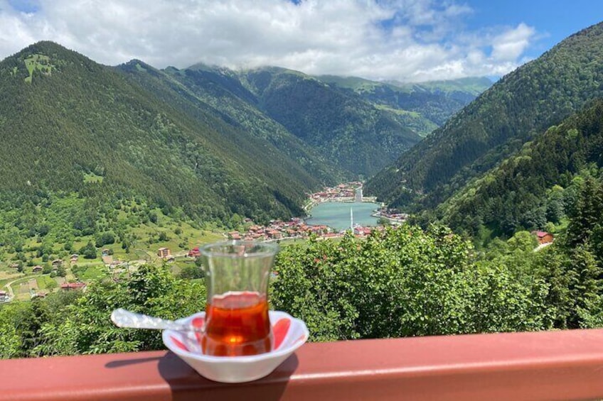 A glass of tea on a table with a scenic view of a valley and mountains in the background. 3