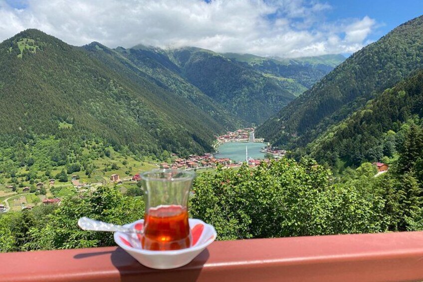 A glass of tea on a table with a scenic view of a valley and mountains in the background. 3