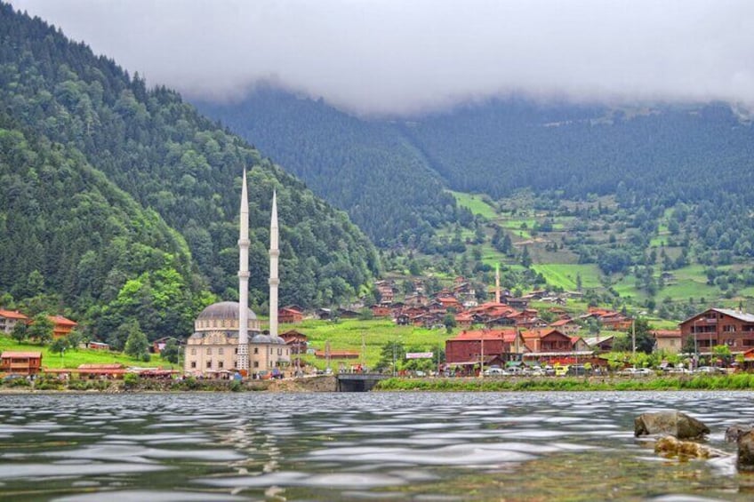 A mosque with two minarets, a river, and a mountainous landscape with a village. 2
