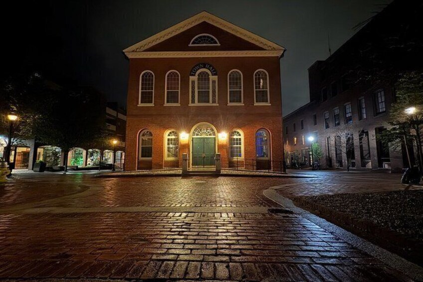 A historic building with a central entrance and arched windows, surrounded by a cobblestone plaza. 4