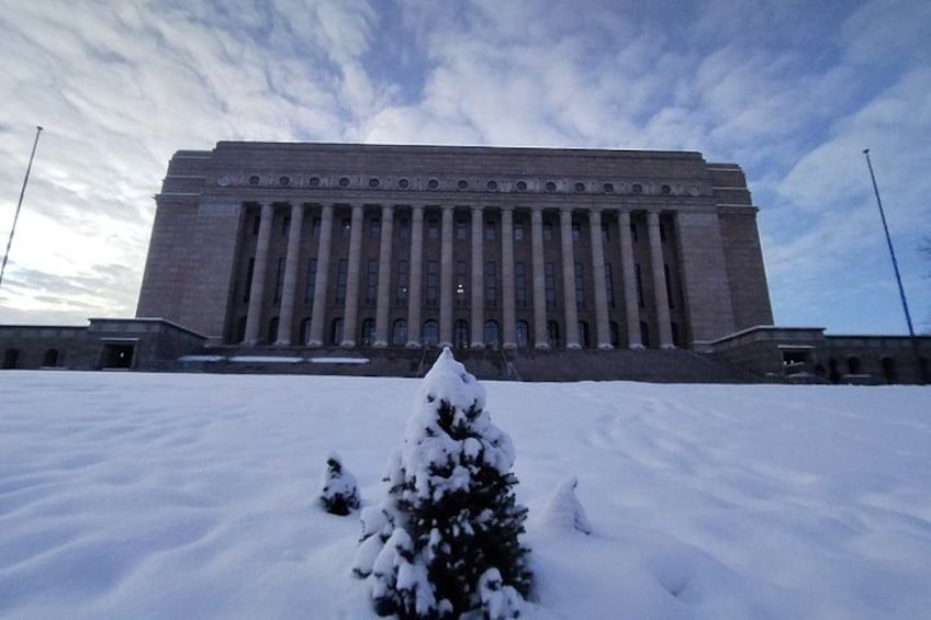 A large, rectangular building with a flat roof and a symmetrical facade, surrounded by snow-covered ground and a few small trees. 5