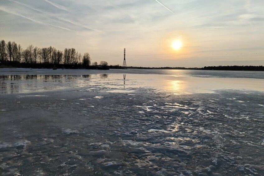 A frozen lake with a tower in the distance and a sunset. 4