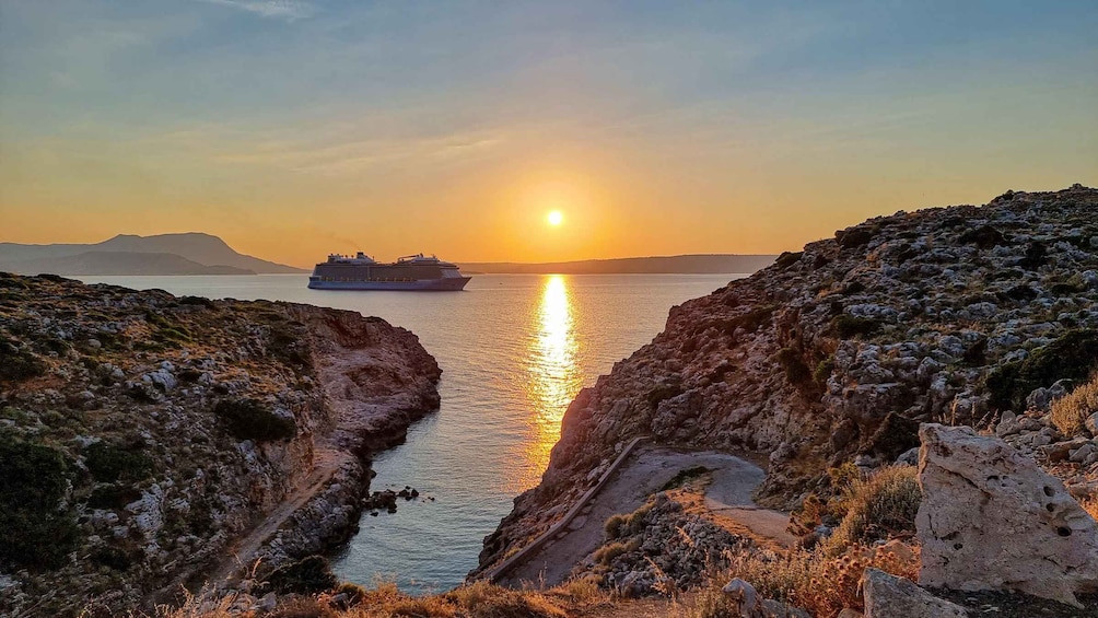A sunset over a rocky coastline with a cruise ship in the distance. 3
