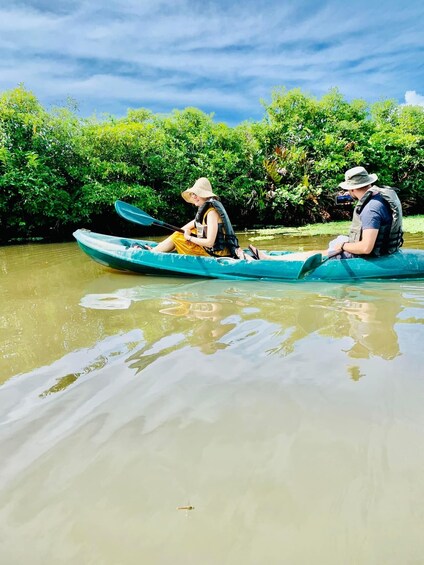 Two people kayaking on a calm river surrounded by lush greenery. 3