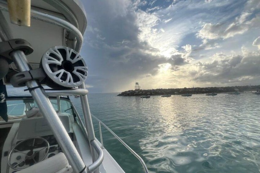 A boat's wheel, calm sea, and a distant shoreline with buildings. 1