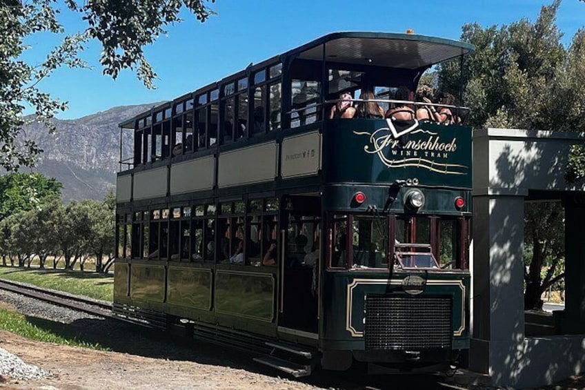 A vintage tram with passengers, traveling on tracks, surrounded by trees and mountains. 5