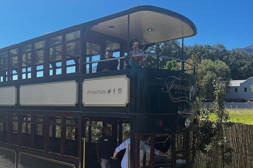 A vintage tram with 'Franken Wine' branding, passengers, and a rural landscape in the background. 4