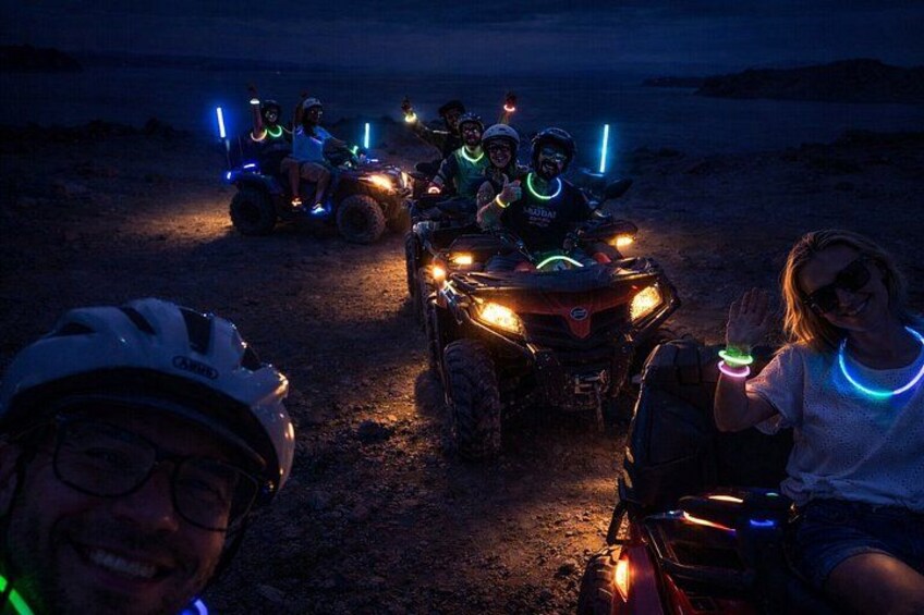 People on ATVs with glowing lights, a helmet, and a person waving. 1