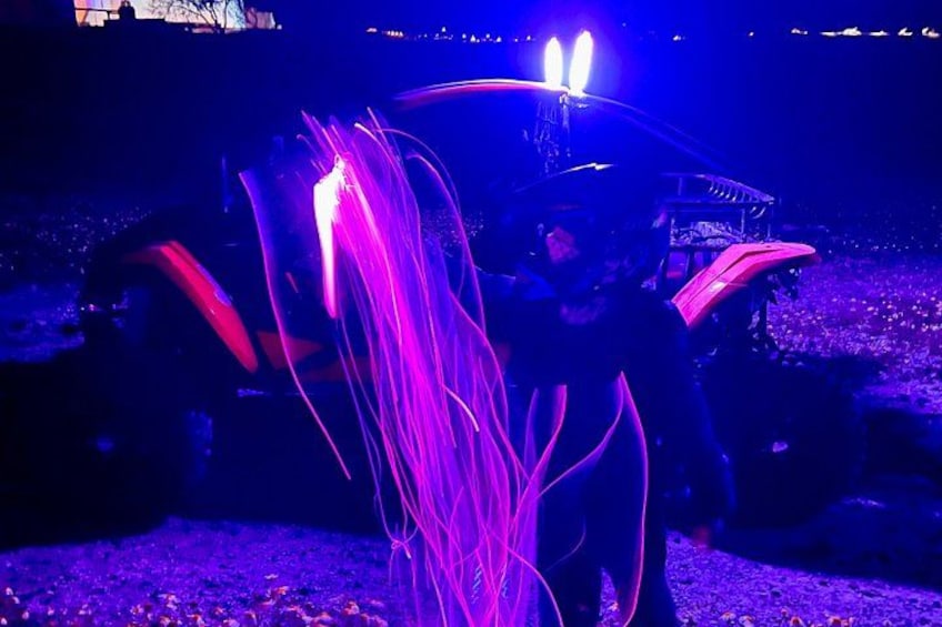 A vehicle with purple and red lights, a person, and a stage in the background. 2
