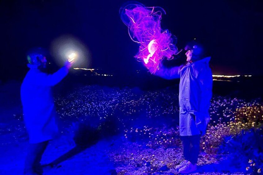 Two people performing an act with glowing objects in a dark outdoor setting. 4