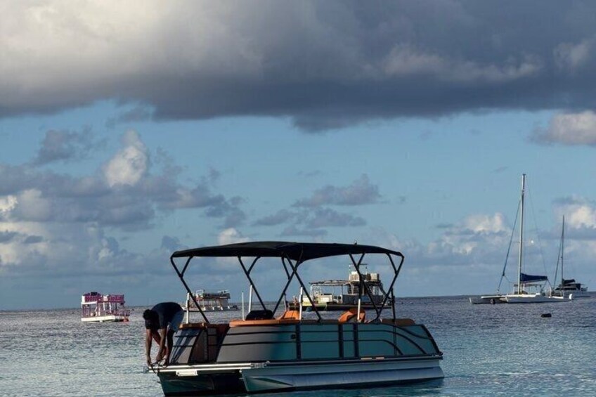 A boat with a person boarding it, another boat in the background, and a sailboat to the right. 4