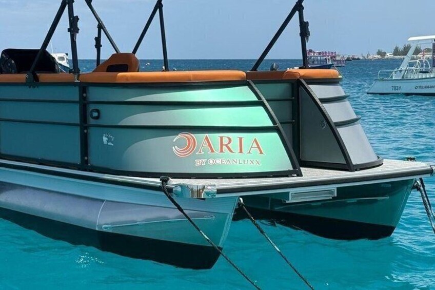A boat named 'ARIA' with a green and orange color scheme, floating on clear blue water. 1