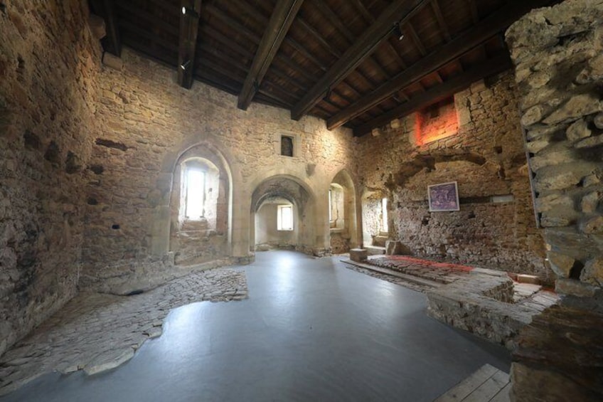 An interior with stone walls, wooden beams, and a stone floor. 4
