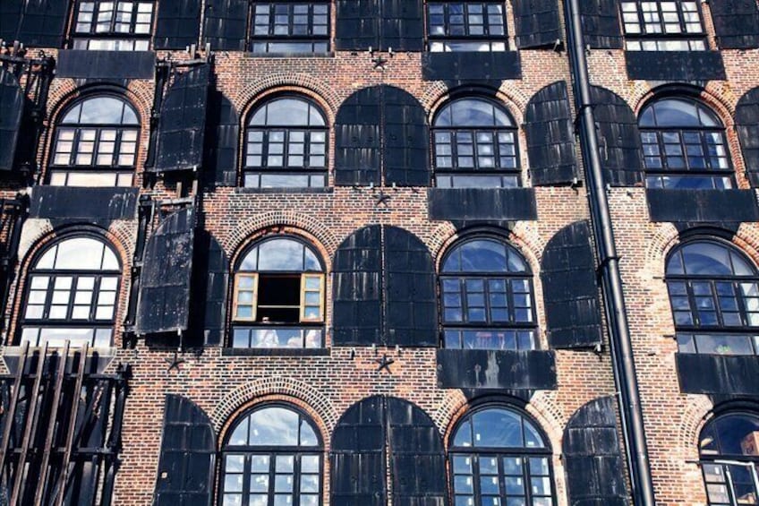 A brick building with arched windows and a black metal pole. 2