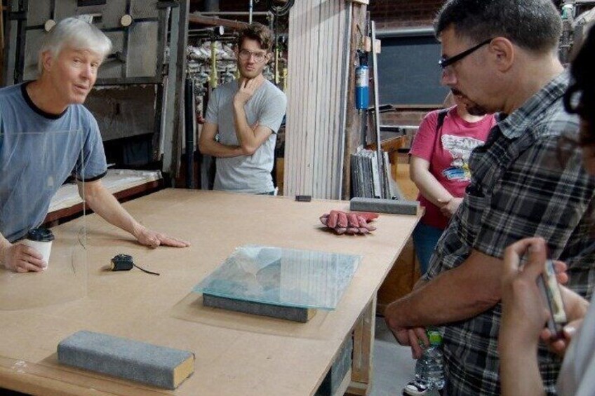 A group of people in a workshop with tools and materials on a workbench. 3