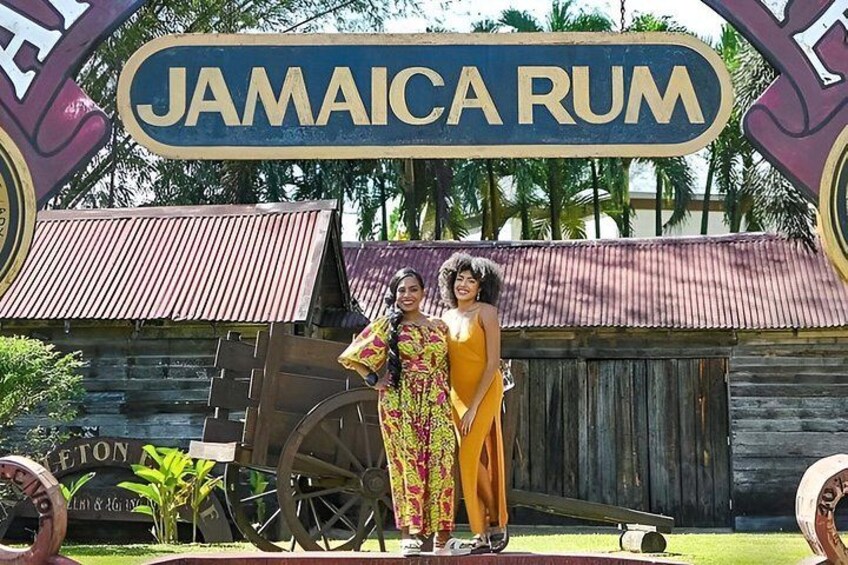 A sign reading 'JAMAICA RUM' with a wooden structure and a cart in the background. 3