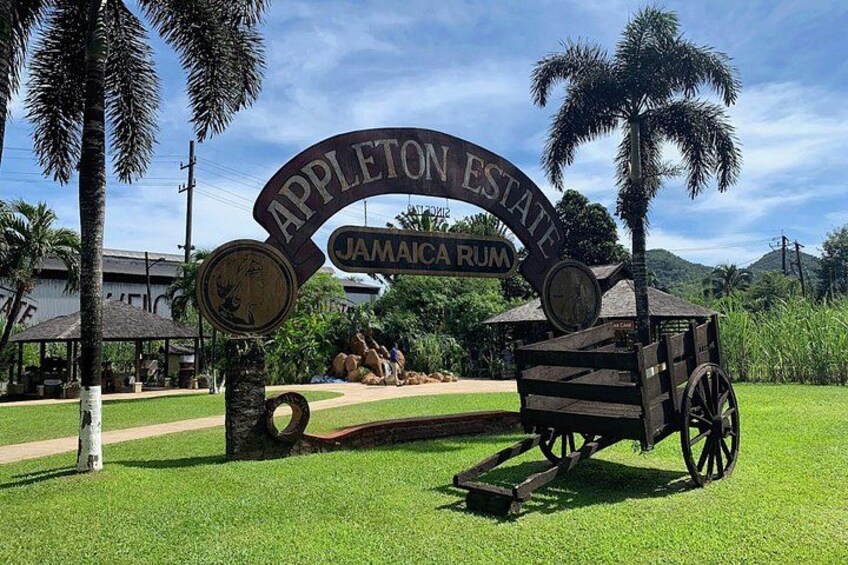 A sign for Appleton Estate Jamaican Rum with a wooden cart and palm trees. 2