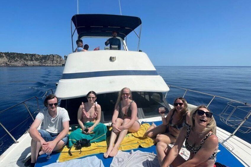A group of people on a boat with a clear blue sky and calm sea in the background. 2