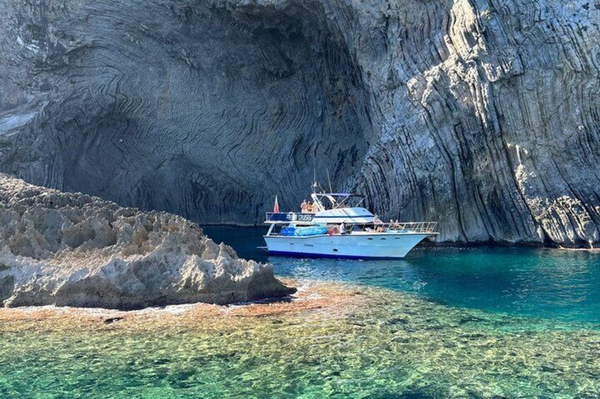 A boat near a rocky coastline with clear water. 1