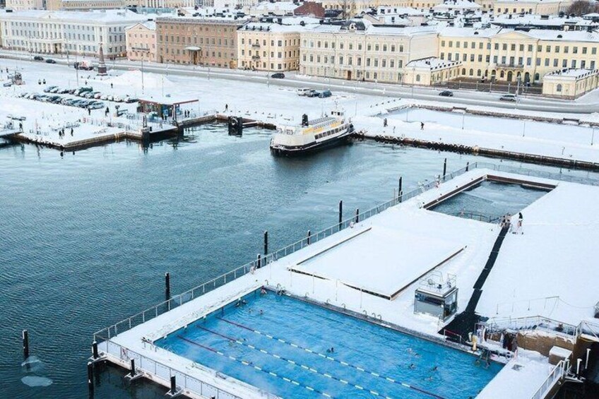 A swimming pool with a boat docked nearby, surrounded by buildings and a snowy landscape. 5