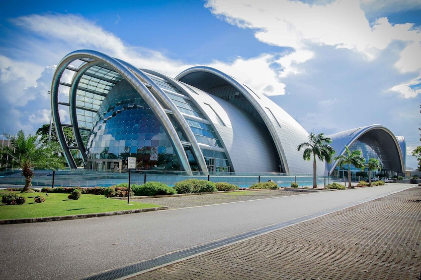 A modern architectural building with curved glass facades and palm trees in the foreground. 2