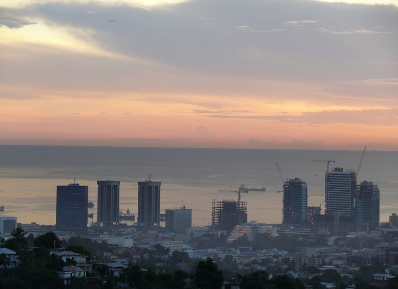 A coastal cityscape with high-rise buildings, construction cranes, and a calm sea during sunset. 5