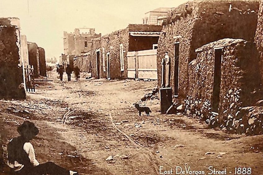 A street scene with buildings, a person sitting on the ground, and a dog. 5