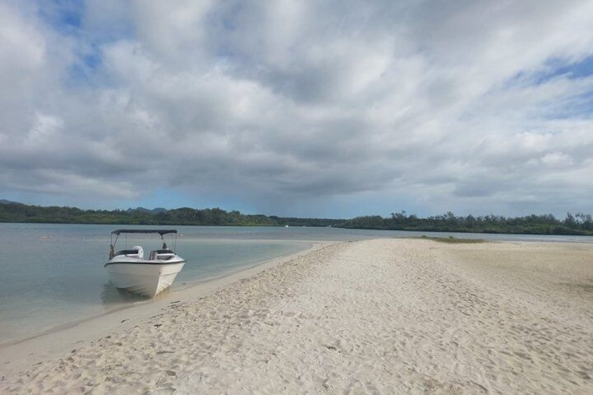 A boat on a sandy beach with calm water and a cloudy sky. 5