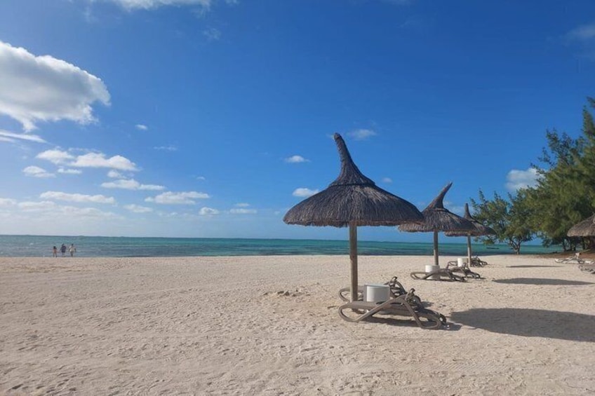 A beach with thatched umbrellas and lounge chairs. 4