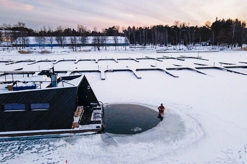 A snowy landscape with a large open water body, a building with a sloped roof, and a person walking on the ice. 1