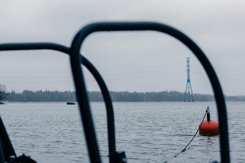 A body of water with buoys and a distant power line tower. 3