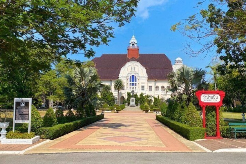 A grand building with a red roof, surrounded by well-maintained gardens and a clear sky. 1