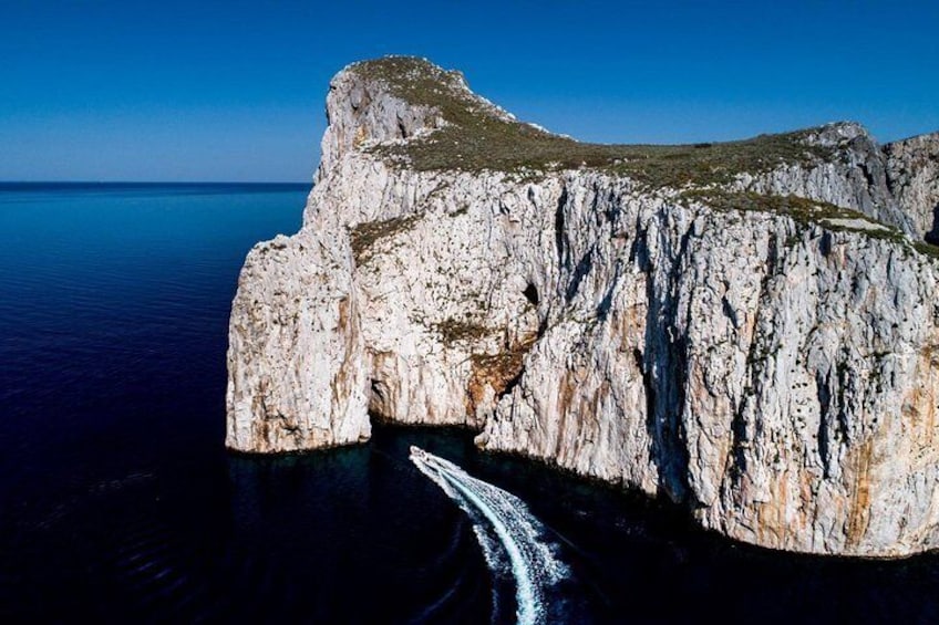 A large rock formation with a boat navigating through a narrow passage. 2
