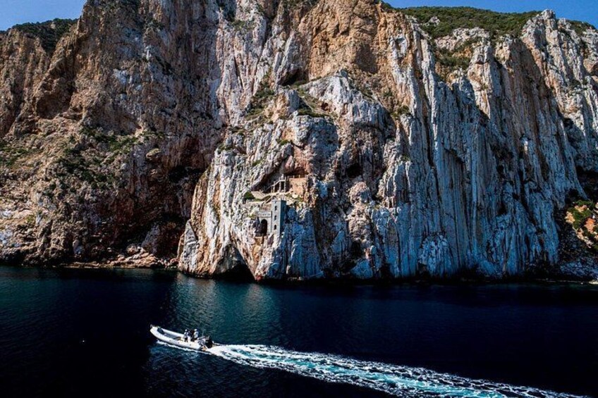 A boat on a calm sea, a rocky cliff, and a clear sky. 3