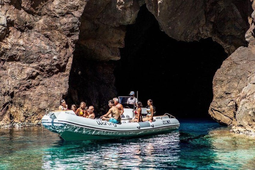 A group of people on a boat near a rocky cave entrance. 5
