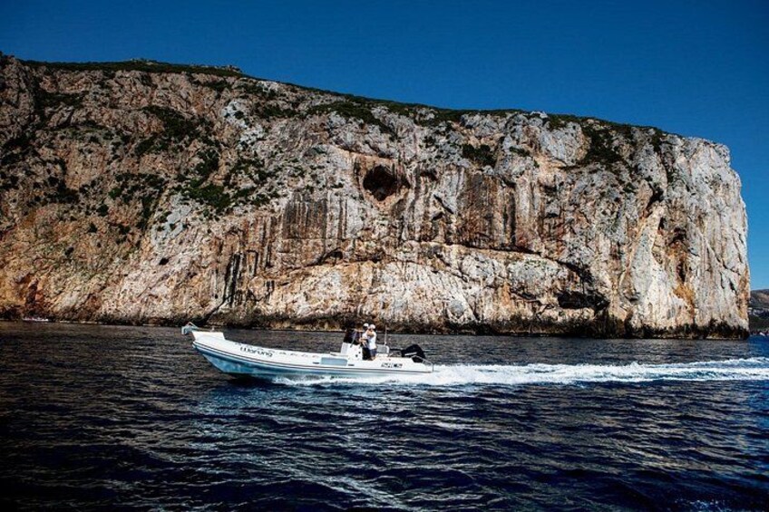 A boat on water with a rocky cliff in the background. 2