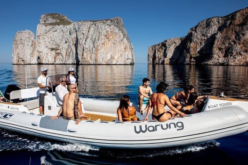 A boat tour with people on a small white boat with 'Warung' written on it, surrounded by rocky cliffs and calm water. 4
