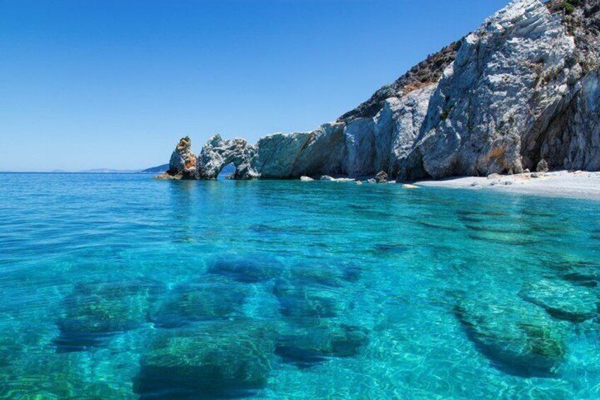 A clear blue sea, rocky coastline, and white sandy beach. 2