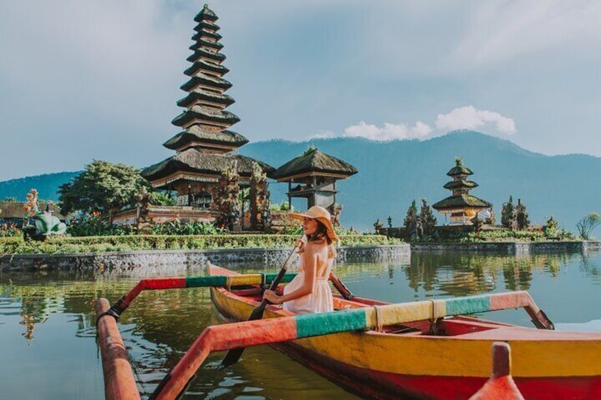 A person in a boat on a calm lake with traditional pagodas in the background. 2