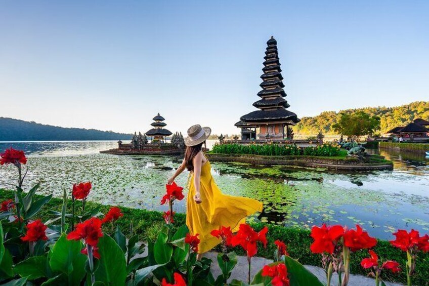 A woman in a yellow dress walking by lotus flowers, with pagodas in the background. 3