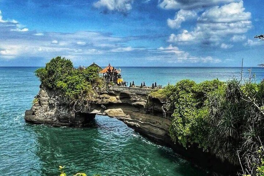 A rock formation with a small building on top, surrounded by water. 1