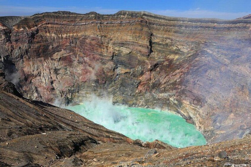 A large crater with turquoise water and steam rising from the bottom. 3
