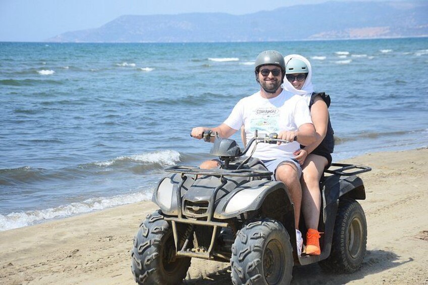 A person riding an ATV on a sandy beach with the ocean in the background. 5
