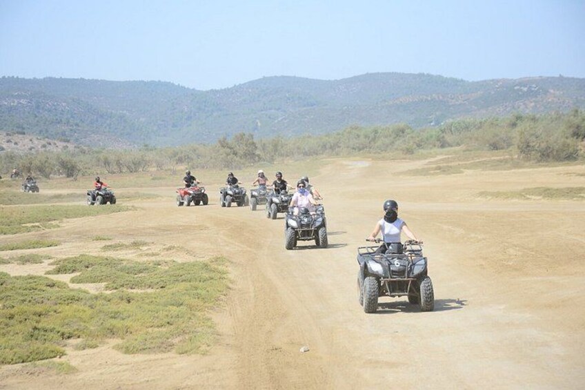 A group of people riding ATVs on a dirt road in a hilly, open landscape. 4