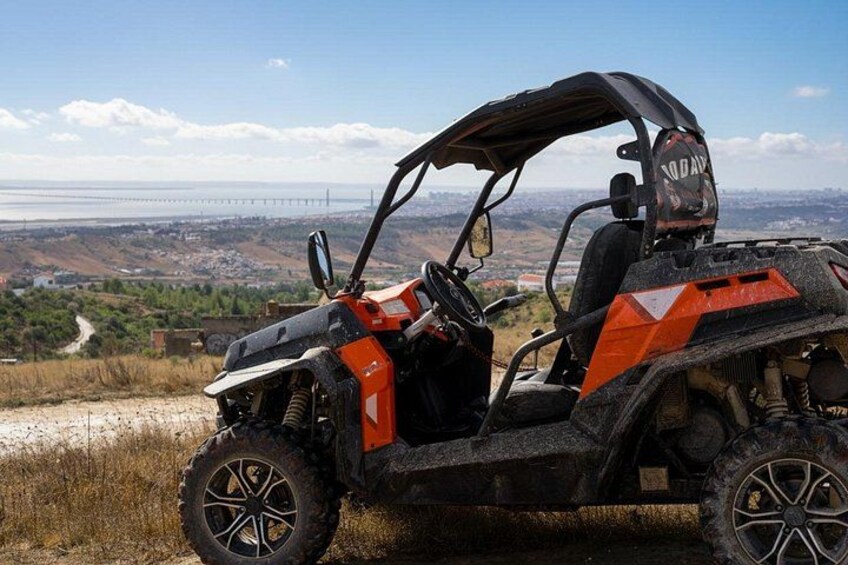 An off-road vehicle on a dirt path with a bridge in the background. 1
