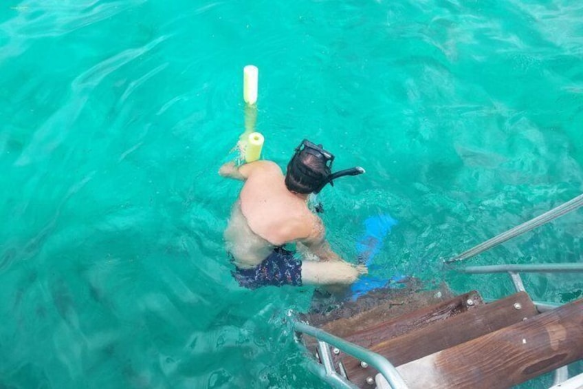 A person snorkeling in clear turquoise water, holding a snorkel and mask. 4