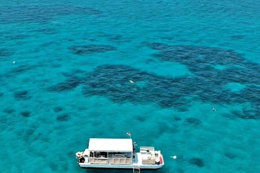 A boat on clear turquoise water with visible coral formations. 2