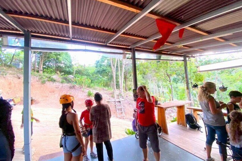 An outdoor covered area with people standing and conversing. 2
