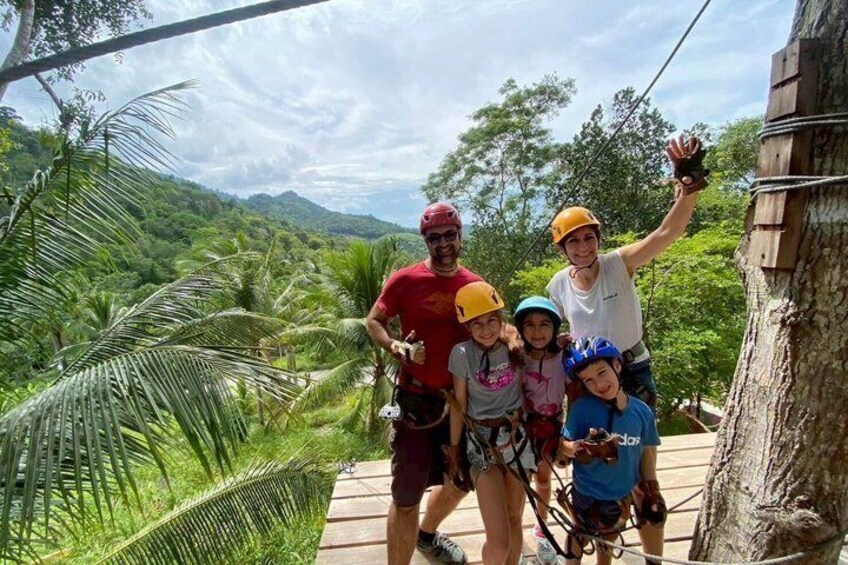 A group of people on a zipline with a tropical landscape in the background. 4