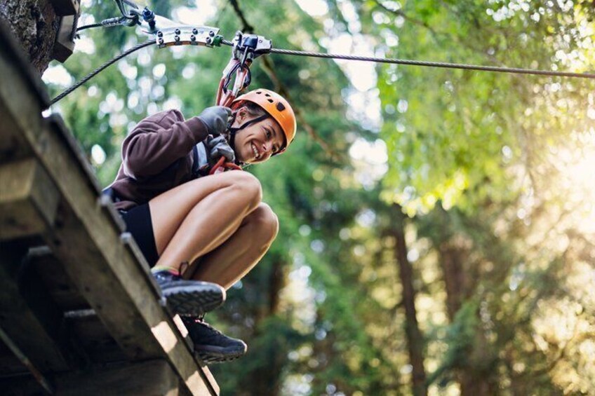 A person rappelling down a wooden structure in a forested area. 5